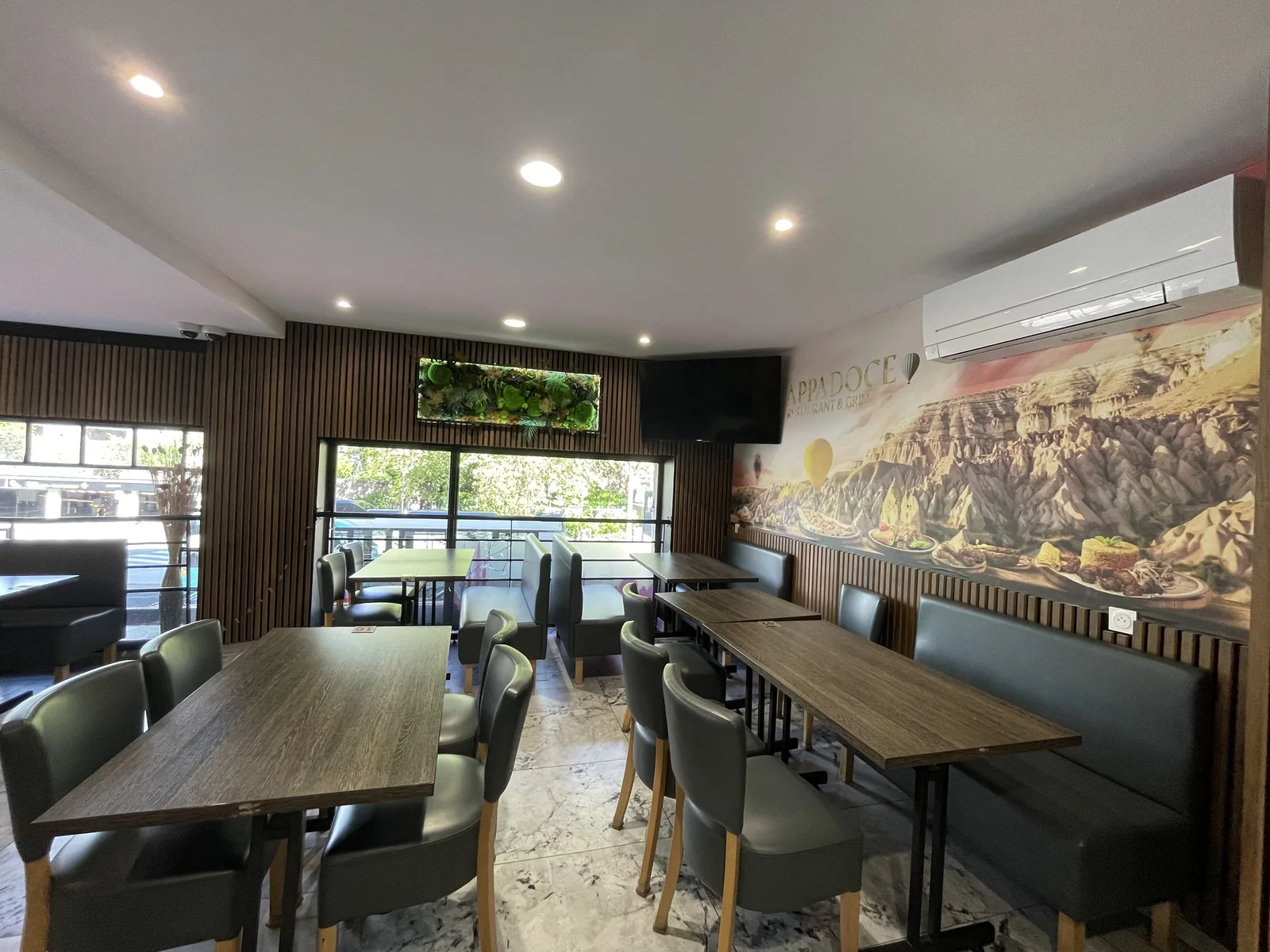 Salle du restaurant turc Cappadoce à Grenoble, 8 rue de Belgrade — banquettes vertes, tables en bois, fresque murale des paysages de Cappadoce, lumière naturelle
